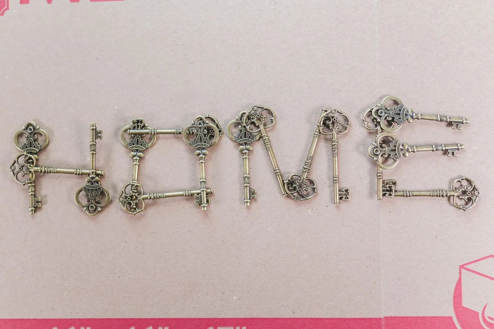 Artistic arrangement of vintage keys spelling 'HOME' on a cardboard surface, creating a rustic still life.